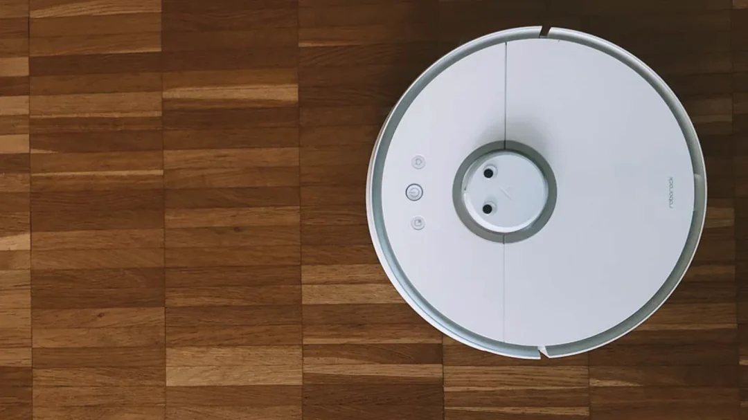 A white robotic vacuum cleaner on a polished wooden floor, representing the diverse product ranges and the 8x profit-to-spend ratio achieved for Microtech Filters.