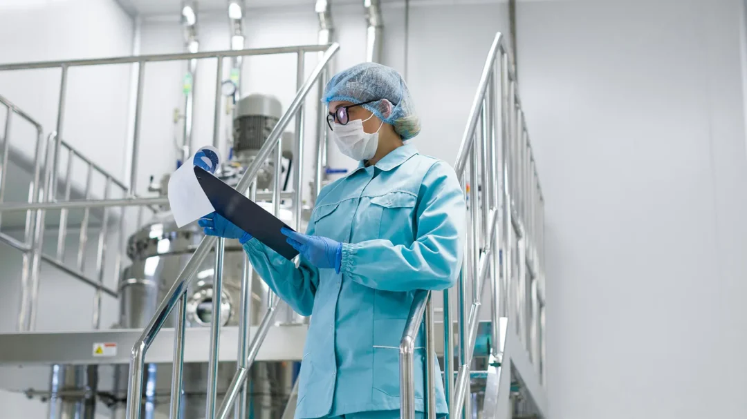 A specialist in protective medical attire reviewing a checklist in a sterile cleanroom facility, representing the high-precision sectors targeted by Repeat Digital’s 103% revenue-growth strategy for Cleanroomshop.