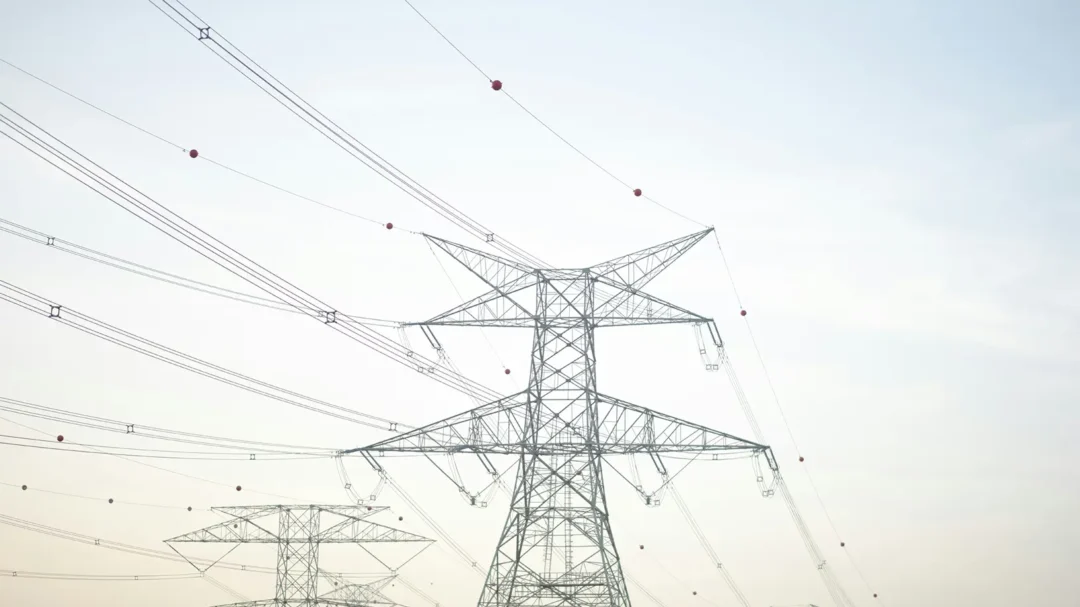 High-voltage electricity pylons and overhead power lines against a clear sky, representing the large-scale utility infrastructure projects managed by Connectus Utilities.