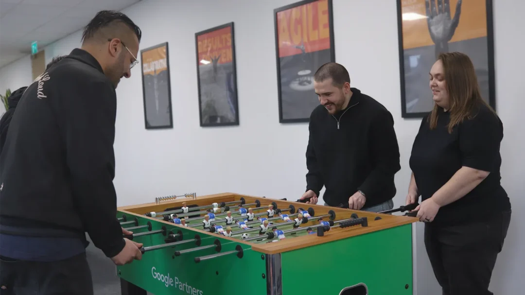 Three Repeat Digital team members playing table football in their Nottingham office, showcasing a collaborative and fun agency culture.