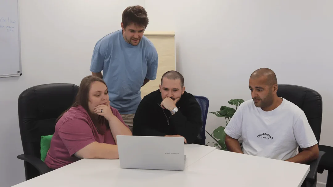 Four Repeat Digital team members collaborating on a LinkedIn ads strategy in a modern office meeting room.