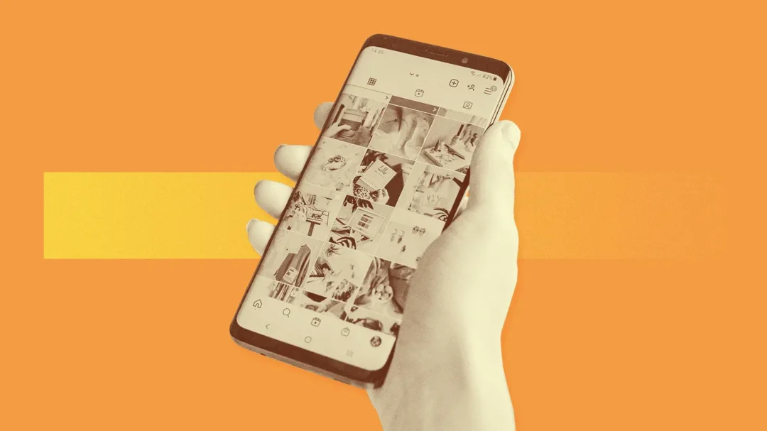 A hand holding a smartphone displaying an Instagram grid feed, representing visual storytelling and mobile advertising on Meta platforms.