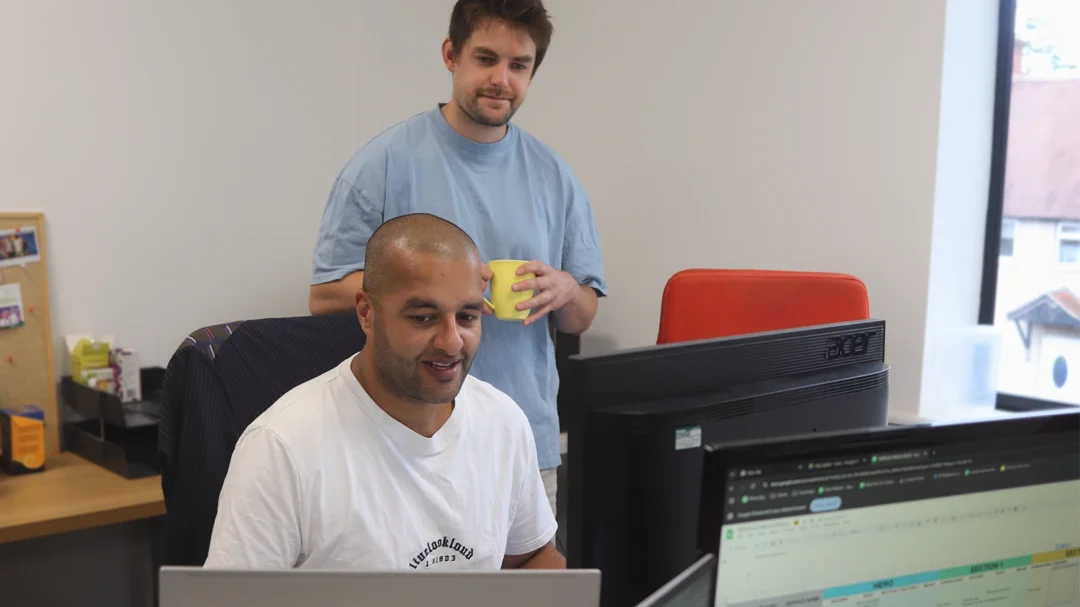Two Repeat Digital team members reviewing a data spreadsheet on a computer monitor in their office.