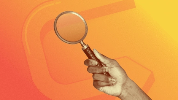 A hand holding a magnifying glass, representing targeted Paid Search and PPC discovery.