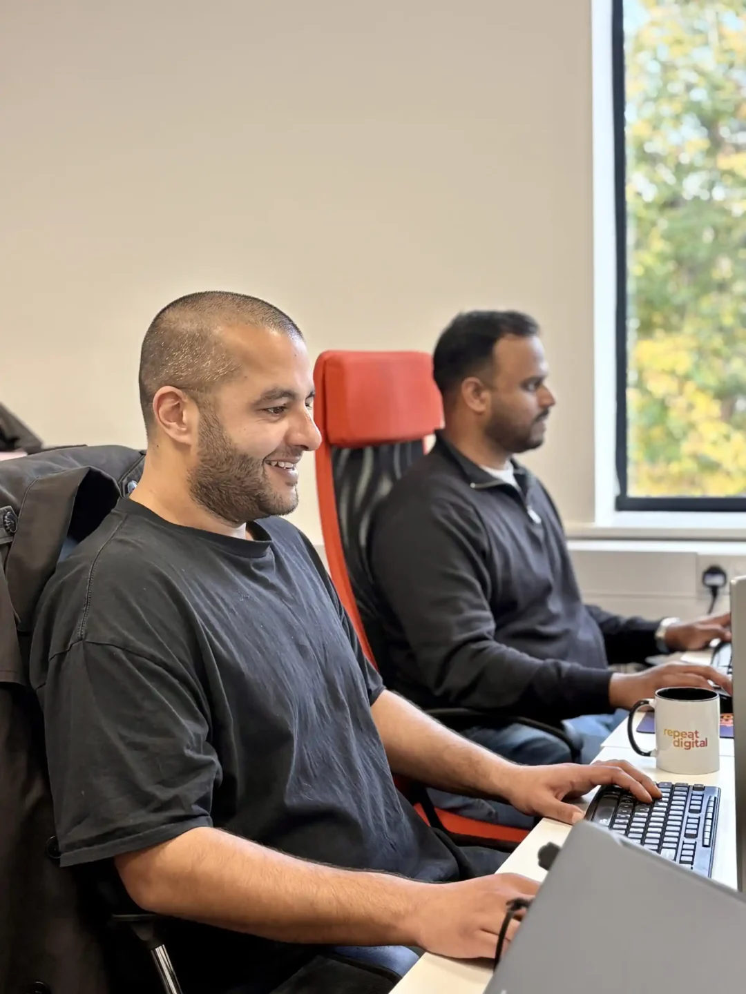 Two digital marketing experts collaborating at a desk in the Repeat Digital office, reviewing social media campaign data.