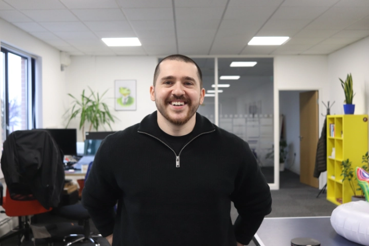 A portrait of a smiling male digital marketing expert at Repeat Digital, standing in a modern office environment.